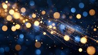 Glowing golden and blue bokeh lights with shimmering sparkles and light trails against dark background create magical festive atmosphere.