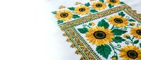 Traditional Ukrainian embroidered towel with sunflower pattern and geometric border on white fabric background for cultural decoration projects.