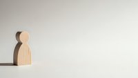 Minimalist wooden human figure casting shadow on white background representing loneliness, isolation, and personal growth concepts for mental health designs.