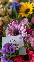 Colorful flower bouquet with I'm sorry apology card featuring pink gerbera daisy, purple blooms and yellow sunflower for forgiveness and reconciliation.