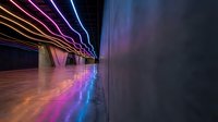 Modern futuristic corridor with vibrant neon light trails creating dynamic motion blur effect on reflective floor surface for technology concepts.