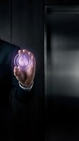 Businessman in dark suit holding glowing power button symbol in palm, representing energy control, technology innovation, and digital startup concepts for business solutions.