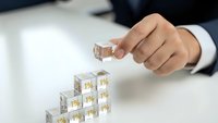 Businessman hand placing wooden cube block on top of pyramid stack for business growth strategy and success planning concept.
