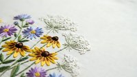 Hand embroidered wildflowers with yellow rudbeckia and purple asters on natural linen fabric showcasing traditional needlework and botanical motifs for crafting projects.