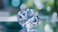 Brilliant cut diamond with reflections on mirror surface against blurred bokeh background. Luxury jewelry concept showing clarity and sparkle of precious gem.