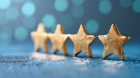 Golden star decorations arranged in row on glittery surface against blurred turquoise bokeh background, creating festive holiday atmosphere for seasonal designs.