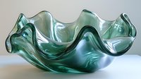 Elegant wavy glass bowl in translucent sea green color with organic flowing form and rippled edges against neutral background, showcasing modern decorative artistry.