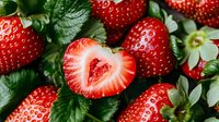 Fresh ripe strawberries with heart shaped cut berry in center, surrounded by green leaves showing natural organic produce for healthy eating concept.