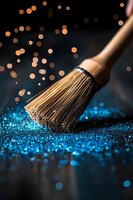 Makeup brush sweeping through sparkling blue glitter on dark background with golden bokeh lights, creating magical cosmetic art effect for beauty industry.