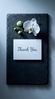 Thank you card with white orchid on dark slate stone, elegant flat lay for greeting, wedding, or appreciation design concepts.