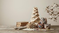 Handmade woven baskets with geometric patterns displayed on wooden table with dried plants and books creating rustic home decor styling composition.