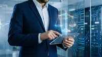Businessman in navy suit holding tablet with digital scales overlay, representing legal technology and compliance solutions for corporate governance.