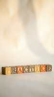 Wooden alphabet blocks spelling PRACTICE arranged in row on neutral surface with soft natural lighting for educational and learning concepts.