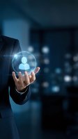 Businessman in dark suit holding glowing digital sphere with user profile icon, representing network connectivity, recruitment, and talent management in corporate environment.