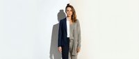 Professional businesswoman in elegant gray blazer and dark pants standing confidently against white background, isolated for corporate design use.