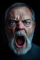 Angry senior Caucasian man with gray beard screaming with wide open mouth showing intense rage and fury against dark background for emotional concepts.