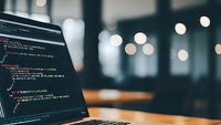 Software developer programming code on laptop screen in modern office workspace with bokeh lights background for technology and coding projects.