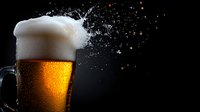 Splashing beer with foam crown in glass mug on dark background with flying drops and dramatic lighting, cold refreshing drink with bubbles and condensation.