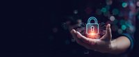 Businessman holding glowing digital padlock with network connections and security icons floating above palm in dark technology background.