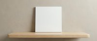 Blank white canvas on wooden shelf against beige wall for artwork display and home decor mockup presentation.