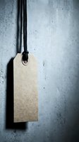 Blank kraft paper price tag hanging on black string against textured concrete wall background for retail branding and product labeling.