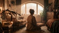 Young woman sitting on floor in cozy sunlit room, meditating near window surrounded by plants and warm vintage decor.