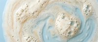 Swirling foam and bubbles create abstract patterns in soapy water with cream and blue tones. Natural cleaning concept for spa and wellness designs.