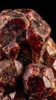 Raw garnet gemstone crystals with deep red burgundy color and natural rough texture on black background for jewelry making and mineral collection.