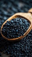 Black rice in wooden spoon on dark background, close-up macro shot of nutritious ancient grain for healthy cooking and gourmet cuisine.