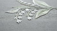 Delicate white embroidered flowers with green leaves on gray fabric showcasing traditional needlework craftsmanship for textile and fashion design projects.