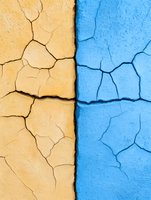 Contrasting yellow and blue cracked wall surfaces divided by straight line, showing weathered texture and natural aging patterns in concrete or plaster material.