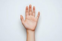 Open palm of a light-skinned hand raised against white background, showing clear lines and details of palm, suitable for fortune telling and palmistry concepts.