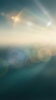Abstract blurred background with soft bokeh lights and lens flares in teal and golden tones for modern design projects and presentations.