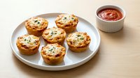 Mini egg muffins with herbs on white plate served with tomato sauce. Perfect breakfast or brunch appetizer for healthy eating and meal prep recipes.
