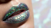 Closeup of lips with iridescent glitter makeup in green and purple tones, featuring sparkly cosmetic application for beauty and makeup artistry projects.