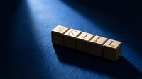 Wooden blocks spelling skills arranged in a row on blue surface with dramatic lighting, representing professional development and competency building.