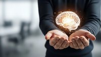 Business professional cupping hands with glowing brain hologram representing artificial intelligence, innovation and mental health concepts in modern office.