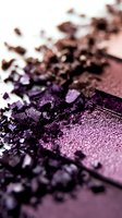 Crushed purple eyeshadow powder with metallic shimmer texture shown in macro close-up, scattered cosmetic pigments creating artistic makeup background.