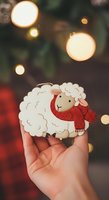 Cute sheep character wearing red scarf held in hand against festive bokeh lights. Isolated illustration suitable for holiday cards, children's designs, and seasonal marketing materials.
