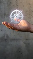 Hand holding glowing compass rose with bright light emanating from palm against textured concrete wall background for navigation and direction concepts.
