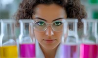 Young African American female scientist in laboratory looking through colorful test tubes, wearing glasses with focused expression and curly hair. Professional research setting.