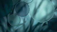 Transparent glass spheres suspended against blurred teal fabric background, showcasing glossy reflective surfaces and light refraction effects for modern design projects.