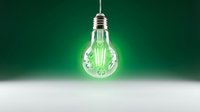 Glowing light bulb hanging from ceiling against green background with white surface below for energy and innovation concepts.