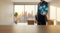 Businessman in dark suit holding glowing digital globe with network connections above wooden desk in modern office with city skyline view through windows.