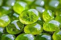 Bright green translucent glass stones or marbles with reflective surfaces in macro photography. Natural light creates sparkle and depth on smooth polished surfaces.
