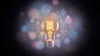 Glowing vintage light bulb with warm filament surrounded by colorful bokeh lights on dark background for creative innovation and inspiration concepts.