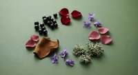 Colorful fabric flower petals and decorative elements arranged on green surface for crafting and DIY projects.