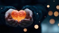 Glowing magical heart shape held in cupped hands against dark background with bokeh lights, symbolizing love, care, hope and emotional healing.