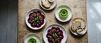 Colorful Middle Eastern mezze spread with hummus, beetroot dip and olives arranged on wooden table from above for healthy Mediterranean dining.