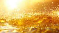 Golden liquid splash with sunlit droplets and waves creating dynamic motion effect against bright background, suitable for beverage advertising and luxury product promotion.